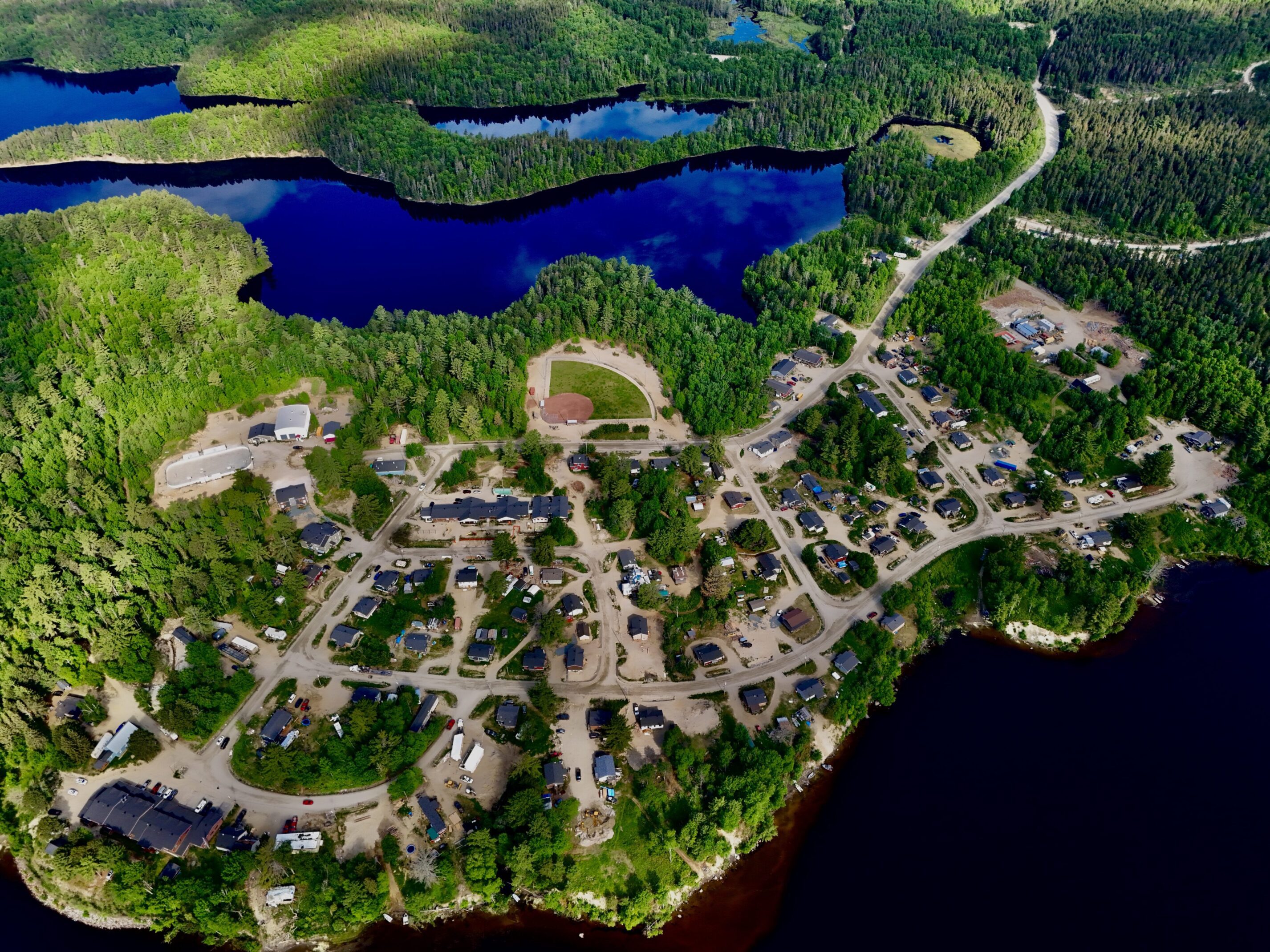 Aerial view of a lakeside village with scattered houses and greenery.