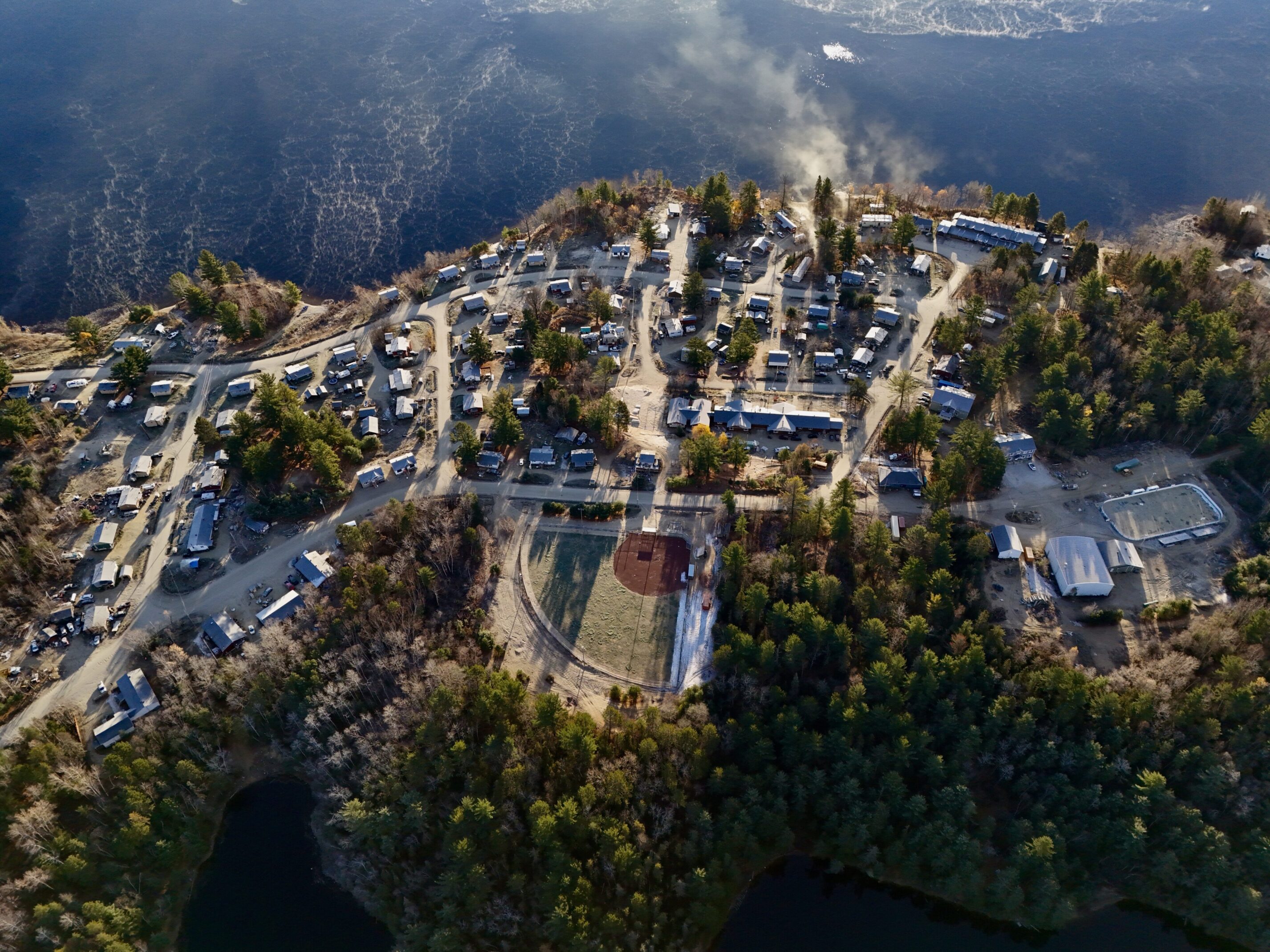 Aerial view of a lakeside village surrounded by forested hills.