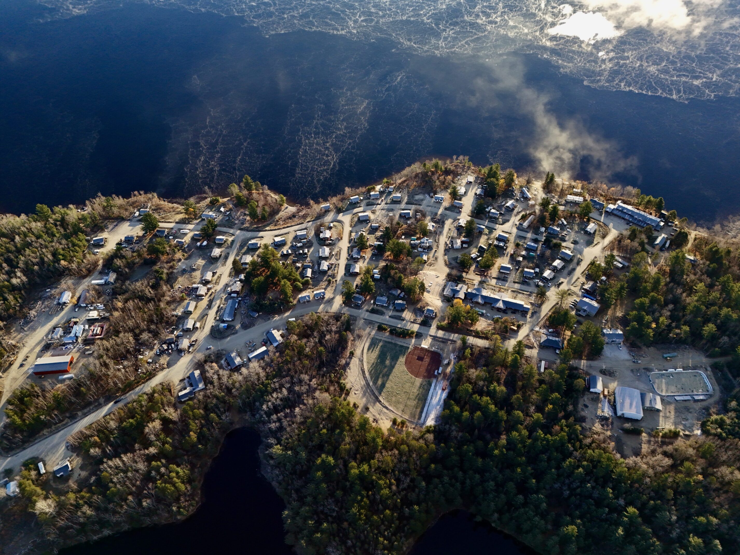 Aerial view of a mountainous village surrounded by trees and water.